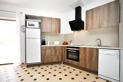 a kitchen with a white refrigerator and wooden cabinets at Apartment Capri by Algarve Vacation in Albufeira