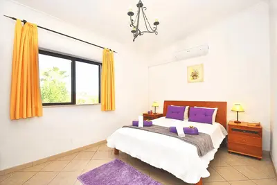 a bedroom with a bed with purple pillows and a window at Villa Sardenha by Algarve Vacation in Guia