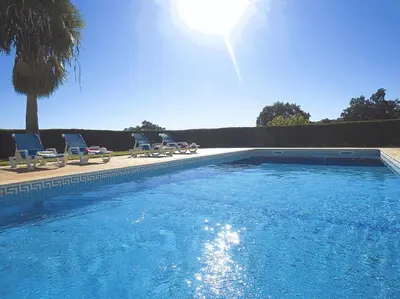a large swimming pool with chairs and the sun at Villa Sardenha by Algarve Vacation in Guia