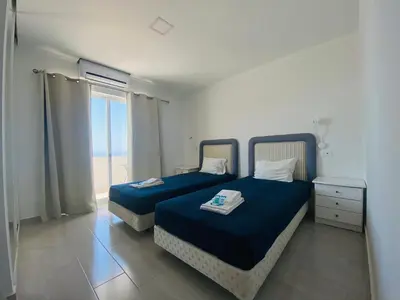 a bedroom with two beds and a window with the ocean at Borda d`Água, Praia da Oura in Albufeira