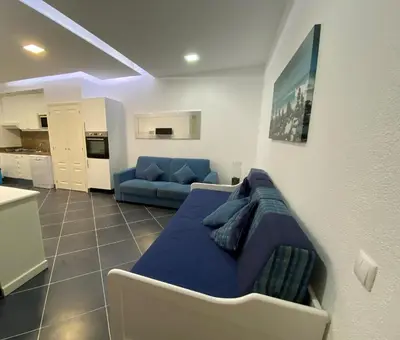 a living room with a blue couch and a kitchen at Borda d`Água, Praia da Oura in Albufeira