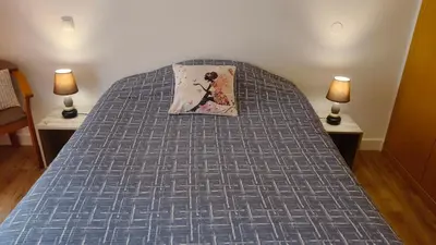 a bed with a blue comforter and two lamps at Rooms_Heart Apartment in Faro