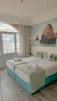 a bedroom with a bed with a painting on the wall at Golden Beach Guest House & Rooftop Bar in Faro