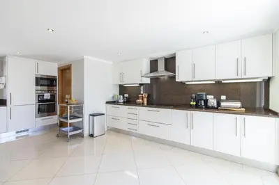 a kitchen with white cabinets and a white tile floor at Villa Vista in Valados