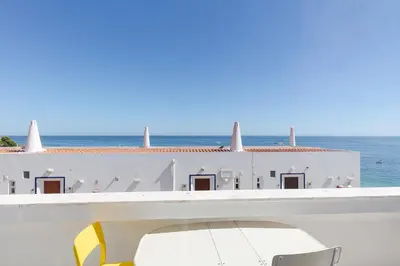 a white building with the ocean in the background at Pé na Praia in Albufeira