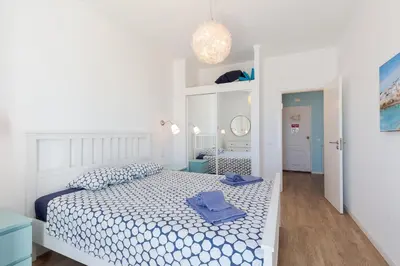 a bedroom with a white bed with blue towels on it at Pé na Praia in Albufeira