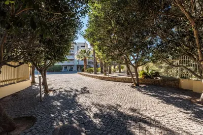 a cobblestone street with trees and a building at Beachfront flat, private parking, pools, sea at less than 200 m in Albufeira