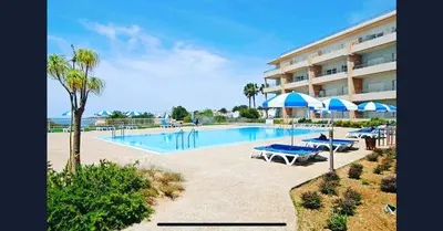 a swimming pool with umbrellas and a hotel at Beachfront flat, private parking, pools, sea at less than 200 m in Albufeira