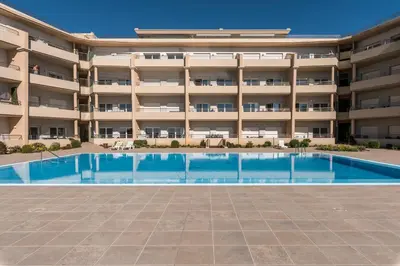 an empty swimming pool in front of a large apartment building at Beachfront flat, private parking, pools, sea at less than 200 m in Albufeira