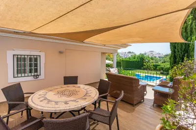 a patio with a table and chairs and a pool at Fonte Santa Villa in Quarteira