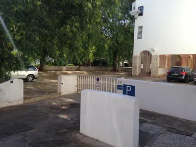 a parking lot with a white fence and a car at Casa Marina in Vilamoura