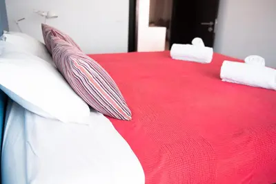 a bed with red and white pillows on it at Wax Suite Life is a beach in Faro