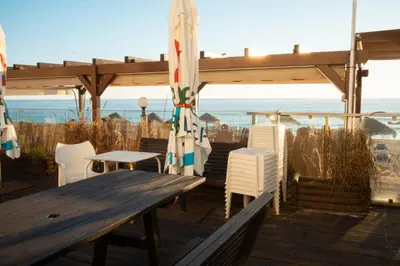 a wooden deck with a table and chairs and an umbrella at Wax Suite Life is a beach in Faro