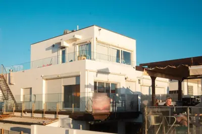 a white house with a man sitting on a balcony at Wax Suite Life is a beach in Faro