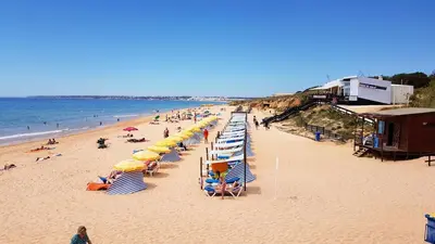 a beach with a bunch of umbrellas and people on it at Oura Lancemar by Sunny Deluxe in Albufeira