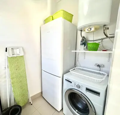 a laundry room with a washing machine and a refrigerator at Casa Marum in Faro