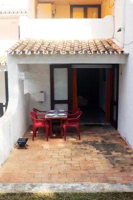 a patio with two red chairs and a table at Acoteias Beach Studio in Albufeira