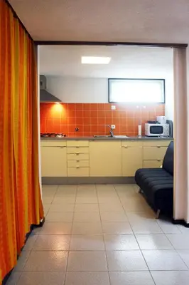 a kitchen with orange curtains and a couch in a room at Acoteias Beach Studio in Albufeira