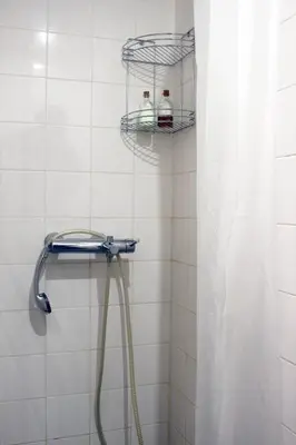a shower with a hose in a white tiled bathroom at Acoteias Beach Studio in Albufeira
