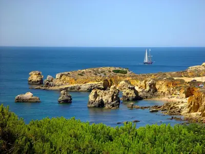 a boat in the water with rocks in the ocean at Marina Coast Residence in Albufeira