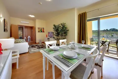 a dining room and living room with a white table and chairs at Marina Coast Residence in Albufeira