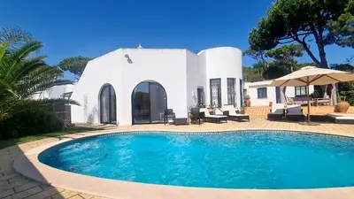 a swimming pool in front of a house at Dunas Douradas Beach Villa in Benfarras