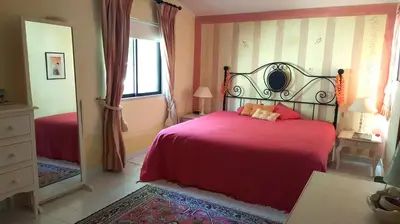 a bedroom with a red bed and a mirror at Dunas Douradas Beach Villa in Benfarras