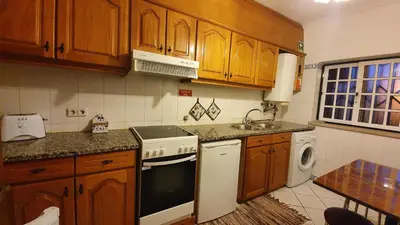 a kitchen with wooden cabinets and a white stove top oven at Tulipa Férias (29506) in Vilamoura
