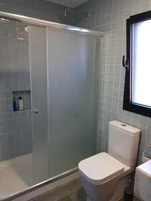 a bathroom with a white toilet and a shower at By the Beach in Almancil