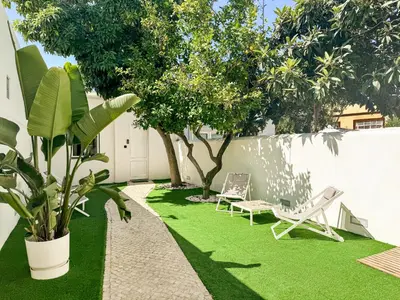 a yard with two lawn chairs and a tree at Dear Faro - Guest House in Faro