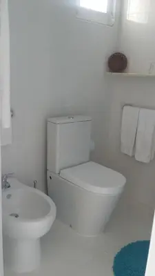 a white bathroom with a toilet and a sink at Balaia Gardens, jardins da Balaia in Albufeira