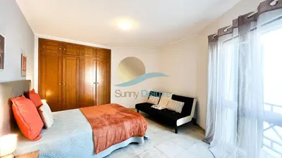 a bedroom with a bed and a chair and a window at Villa Golfinho by Sunny Deluxe in Albufeira