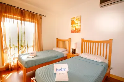 two twin beds in a room with a window at Apartamento Corcovada - By Bedzy in Albufeira