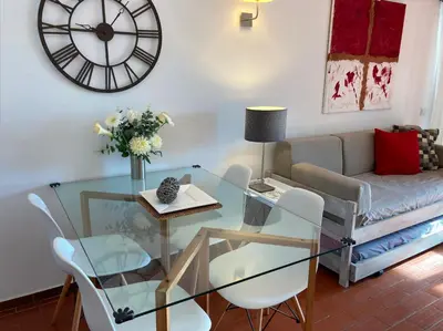 a living room with a glass table and a clock at Urbisol 202-Albufeira in Albufeira