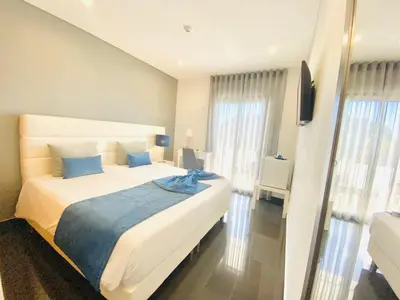 a bedroom with a large white bed with blue pillows at Sunfield Guest House - Only Adults in Albufeira