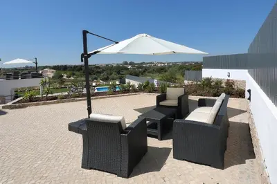 a patio with two chairs and an umbrella at Sunfield Guest House - Only Adults in Albufeira