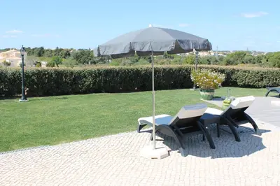 two chairs and a table with an umbrella at Sunfield Guest House - Only Adults in Albufeira