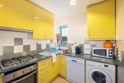 a kitchen with yellow cabinets and a washer and dryer at Funtastic Albufeira Marina 1b3b in Albufeira