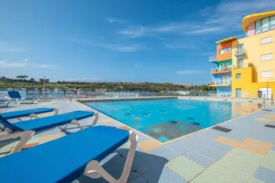 a swimming pool with lounge chairs and a hotel at Funtastic Albufeira Marina 1b3b in Albufeira