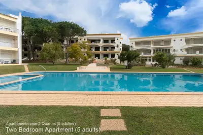 a swimming pool in front of two apartment buildings at Akisol Vilamoura Pine in Quarteira