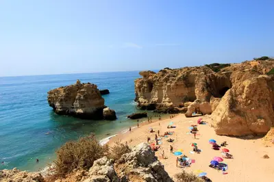 a group of people on a beach near the ocean at Warm Yellow Albufeira in Albufeira