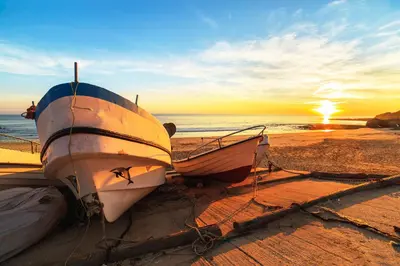 two boats sitting on the beach at sunset at Warm Yellow Albufeira in Albufeira