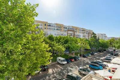 a parking lot with cars parked in front of a building at Warm Yellow Albufeira in Albufeira