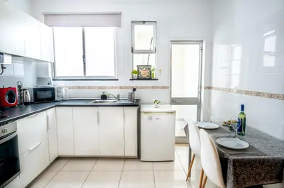 a kitchen with white cabinets and a sink at Reis Turismo in Faro