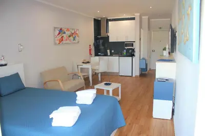 a small room with a blue bed and a kitchen at Vilamoura Dolphin Studio in Vilamoura