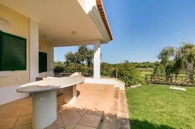 a house with a bench on a patio at Villa Formosa Golf in Quinta do Lago