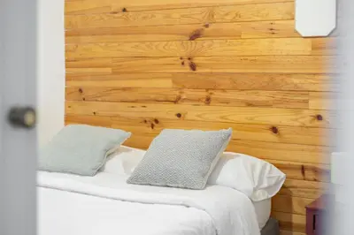 a bed with two pillows on it with a wooden wall at The Central Townhouse in Faro