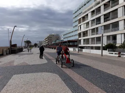 a couple of people riding a bike on a street at Apartamento Quarteira T1 in Quarteira