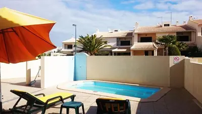 a swimming pool with two chairs and an umbrella at Holiday House in Albufeira