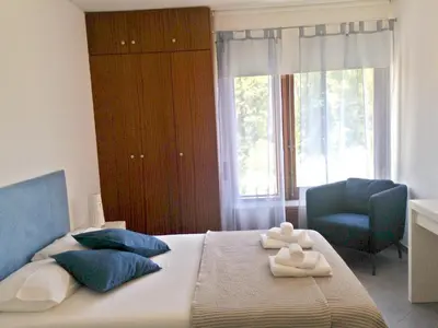 a bedroom with a bed with a blue chair and a window at Casa Balaia in Albufeira